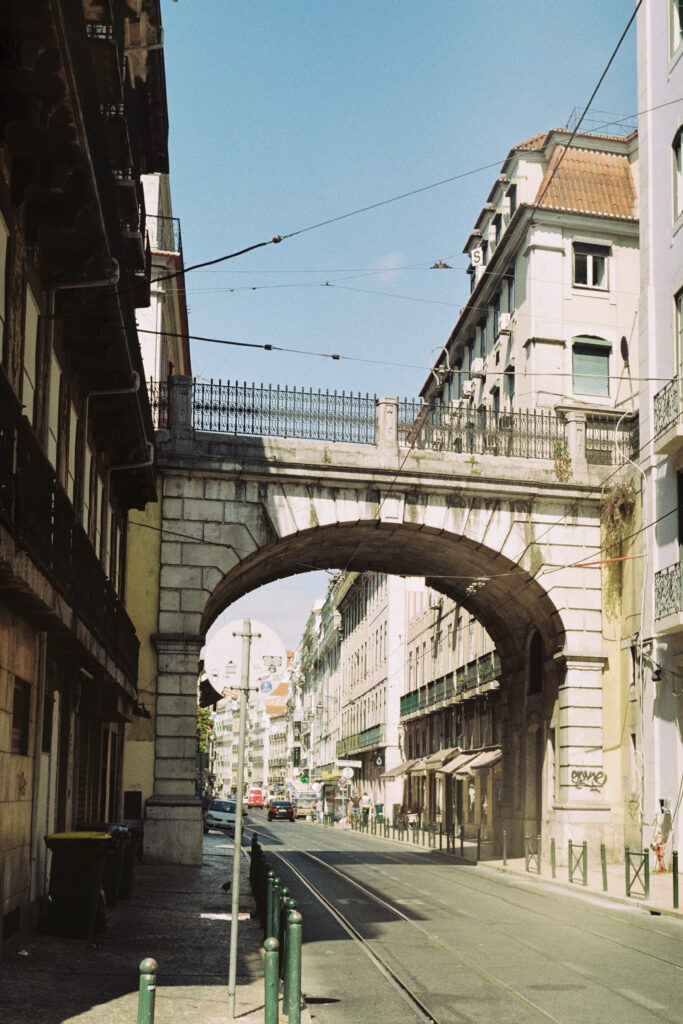 Street in Lisbon where you can see the streetcar tracks a bridge and historic buildings